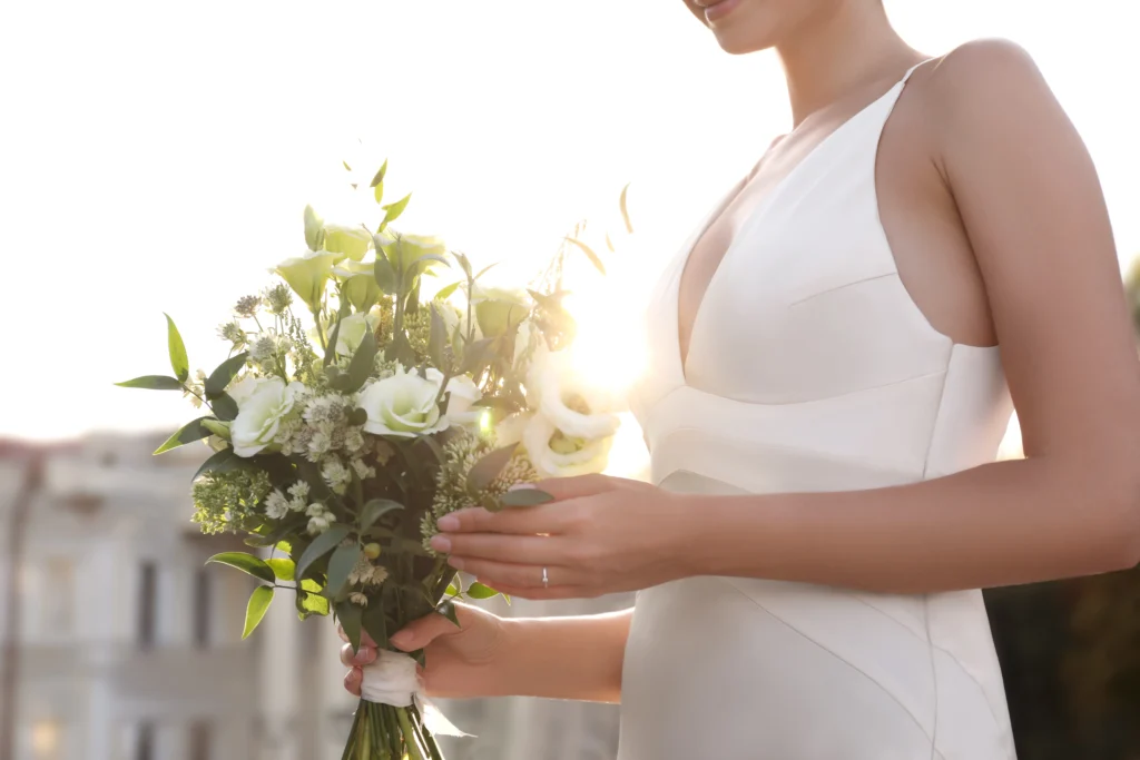 Novia elegante sosteniendo ramo de flores blancas