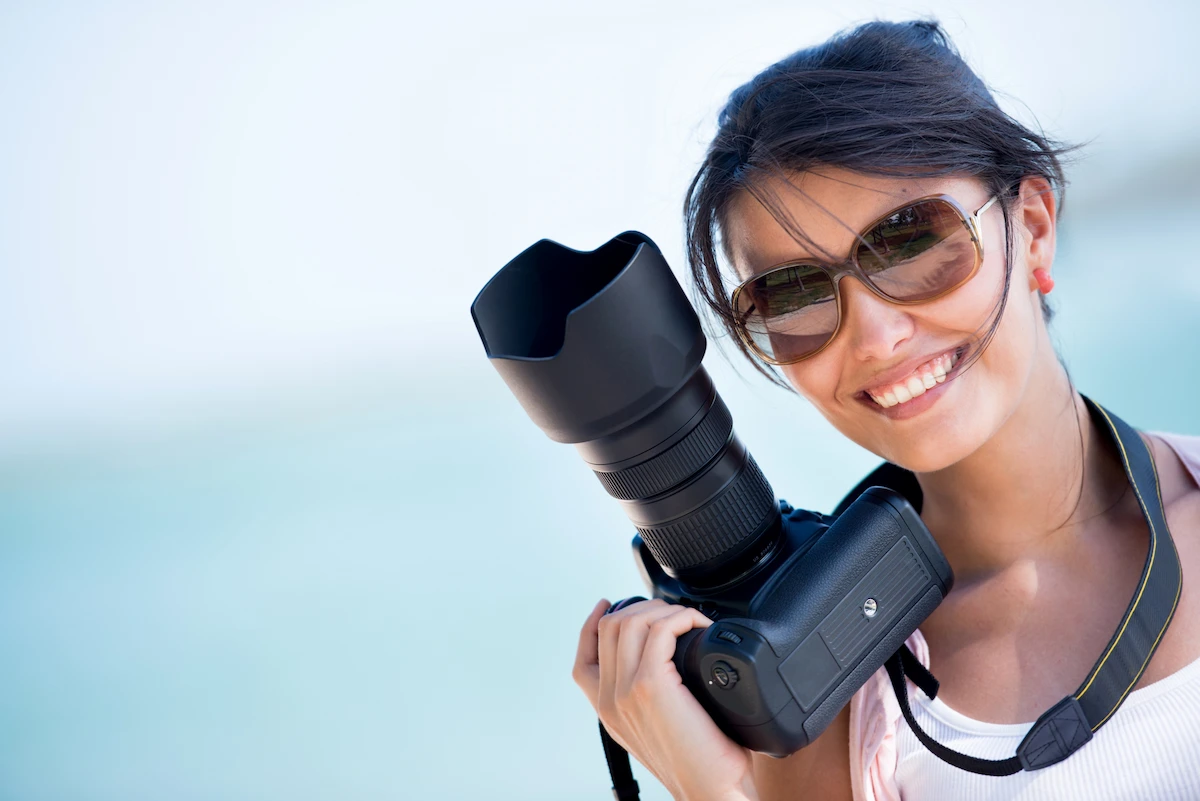 smiling-woman-holding-camera-at-tropical-beach